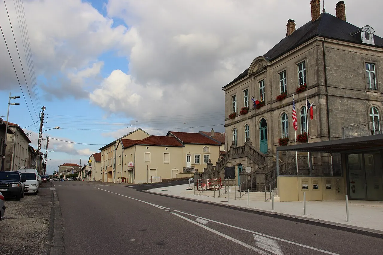 La mairie de Souilly, grande bâtisse de pierre à perron et drapeaux, au bord de la route qui file vers Verdun entre des maisons basses
